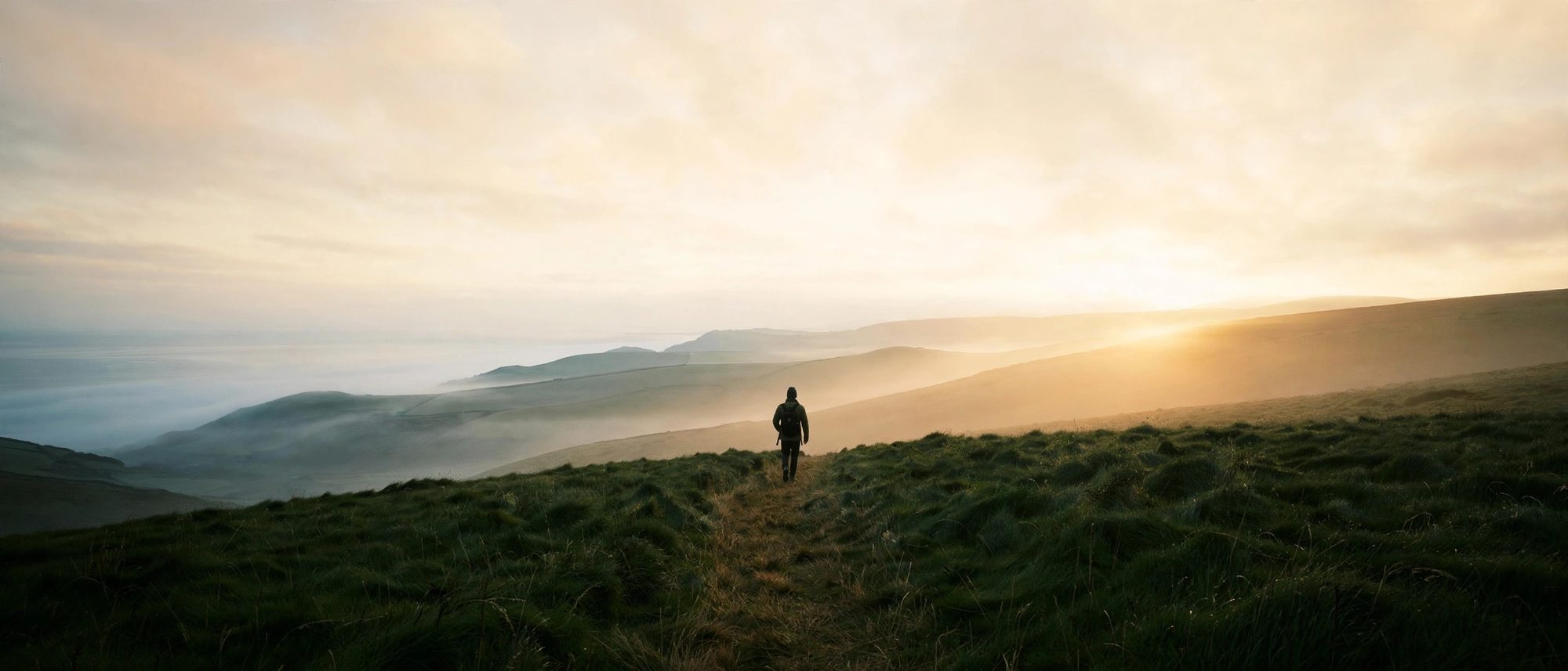 A person walking a coastal path at sunrise